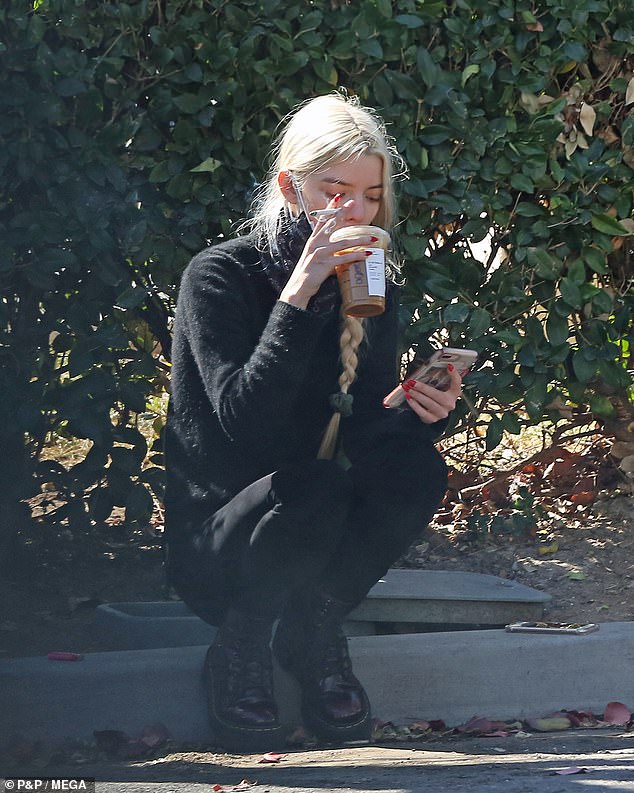 Pop of colour: As she lit a cigarette on her stroll along the street, her eye-catching pointy red nails added a pop of colour to the monochrome outfit