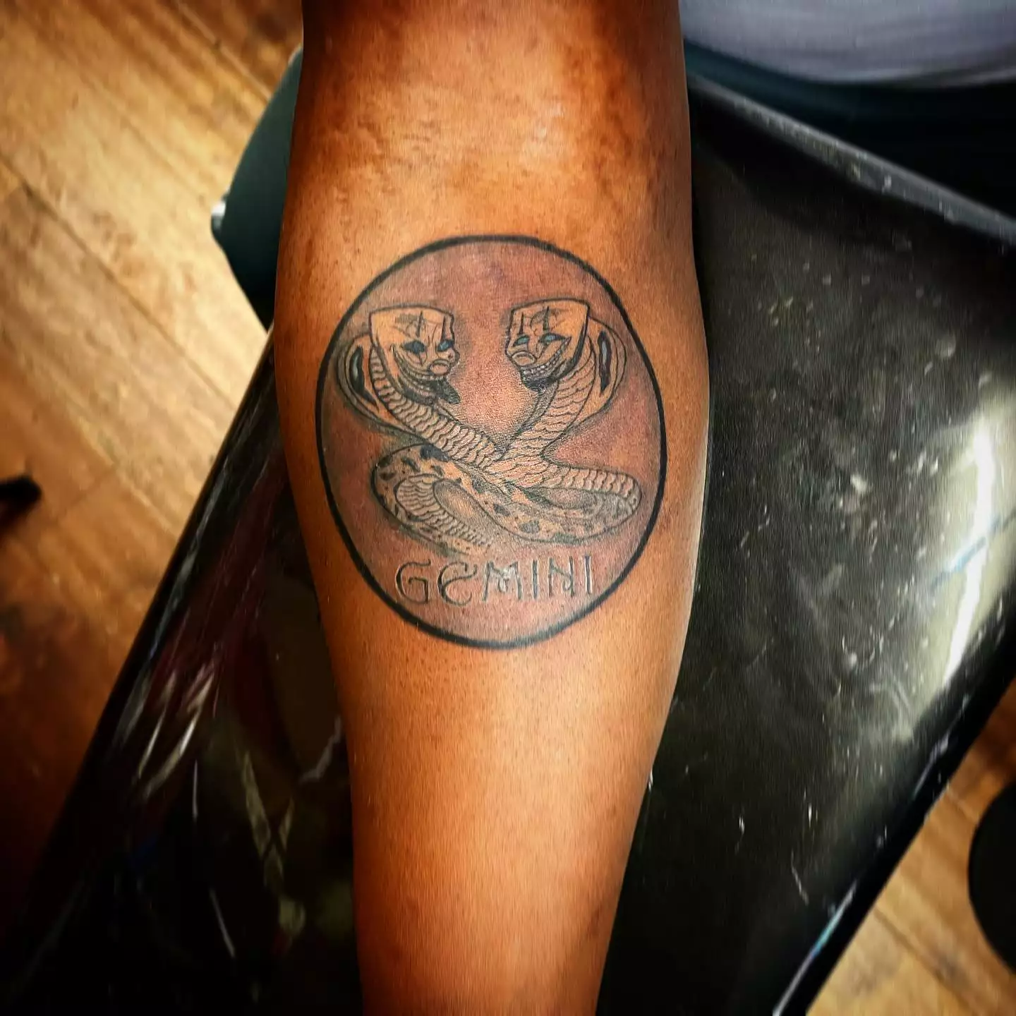 Image of a Gemini tattoo with two intertwining snakes that have clowns as head