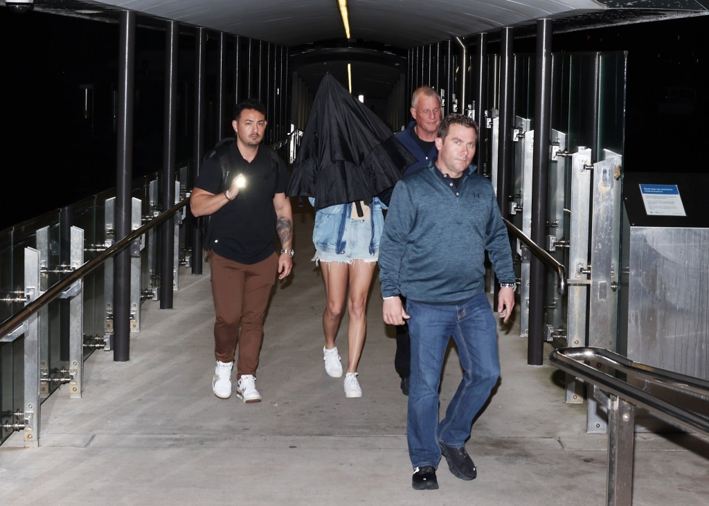 Taylor Swift hiding herself with an umbrella while walking down Neutral Bay Wharf in Sydney with her father and security team on Feb. 26, 2024.