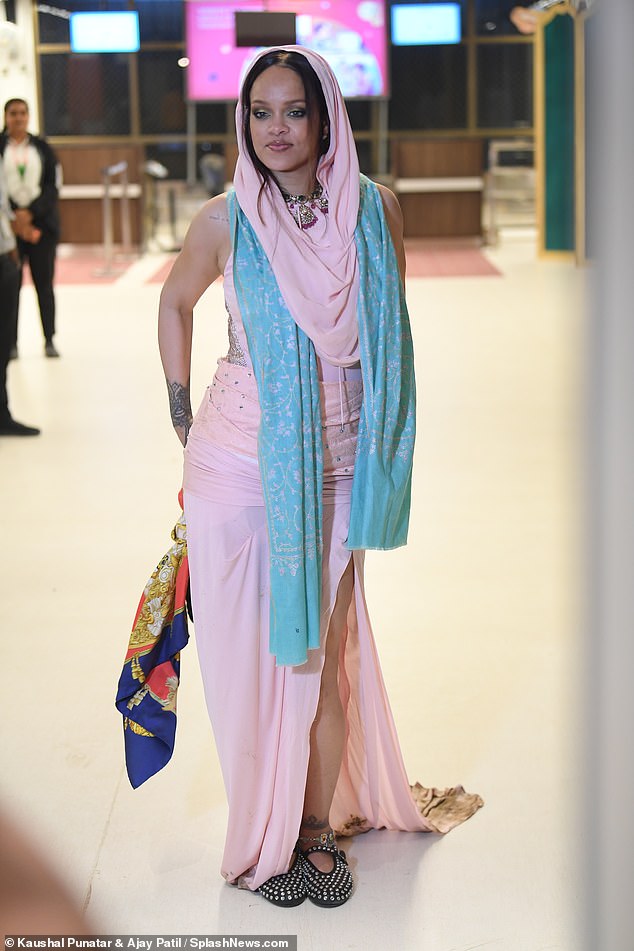 Rihanna se puso un sari rosa con capucha y también lucía una bufanda turquesa.