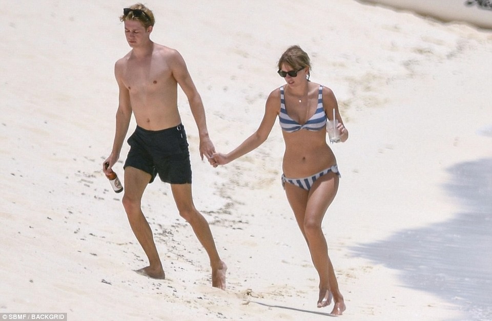  Taylor wore a sexy swimsuit and held Joe's hand while walking on the white sand dunes. The couple looked extremely happy and comfortable. 