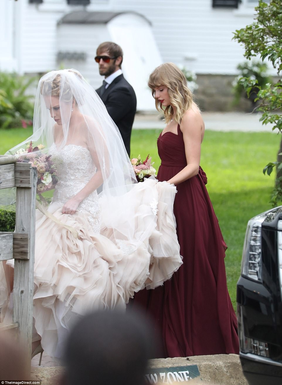 Teamwork: Making more of a statement, the bridal gown then expanded into a dramatic fishnet bottom of bold pink tulle - which was so voluminous it required Taylor's help to carry 