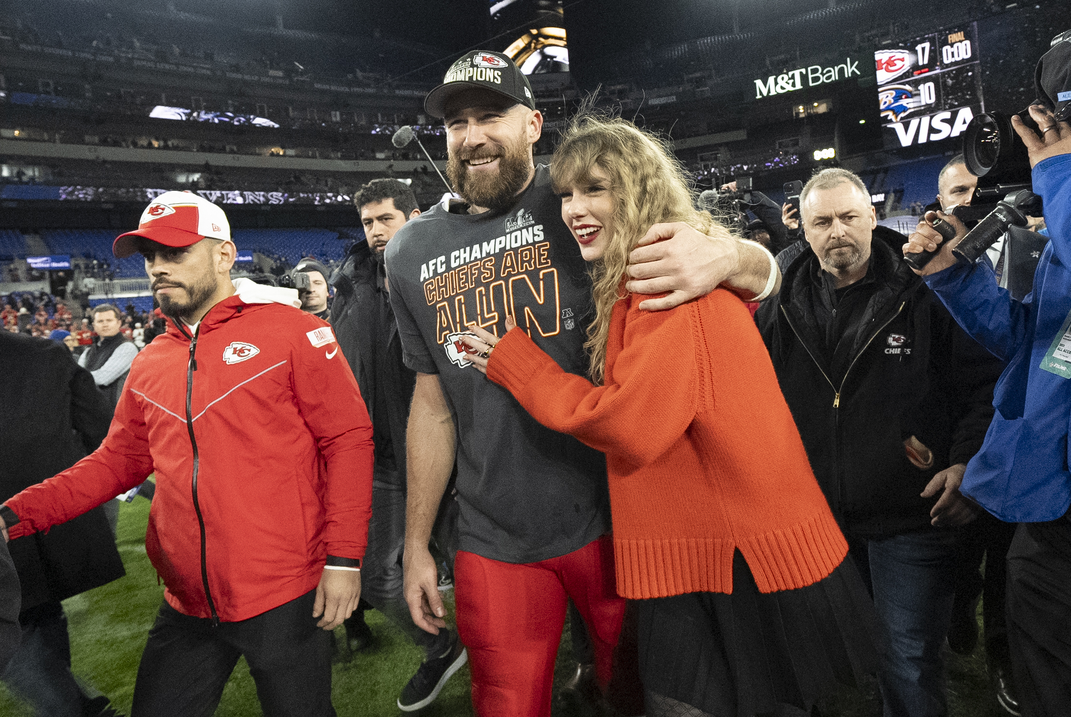 Travis Kelce and Taylor Swift walk together after an AFC Championship NFL football game.