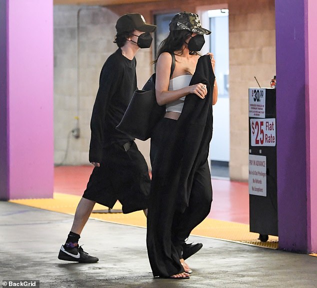 The mother of two showcased her toned midriff in a white crop top paired with black baggy pants, complemented by a baseball cap and a facial mask