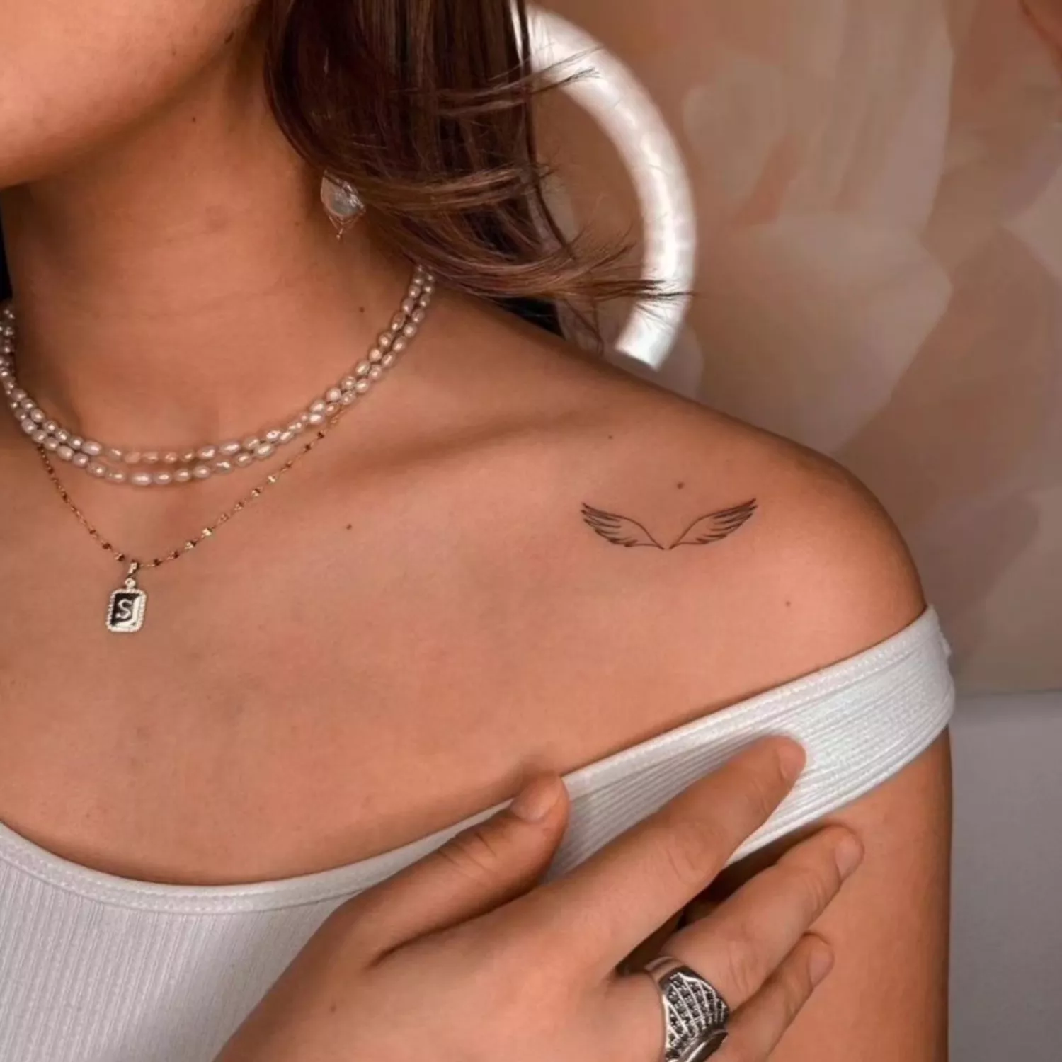 zoomed-in image of model with black ink angel wings tattoo on collarbone