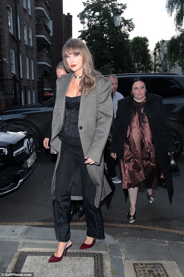 Taylor looked gorgeous in a black corset layered under a tailored grey coat and accessorised with a choker necklace and towering heels to match her lipstick shade