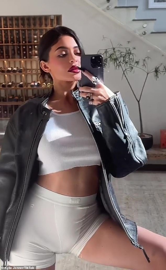 Selfie time: Kylie Jenner flaunted her taut tummy in a white tank top chopped into a crop-top and matching Y-front biker shorts on Sunday