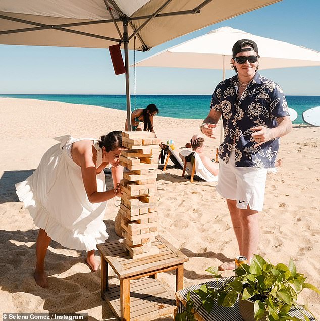 Game time: Selena was pictured enjoying an exciting game of Jenga with Brooklyn as they spent time on the sandy shore with other close pals