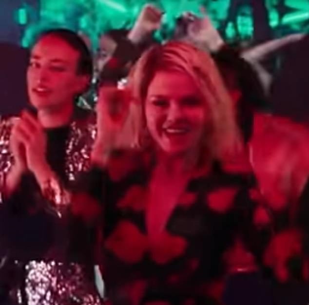 She seems to be having fun as she dances with the women